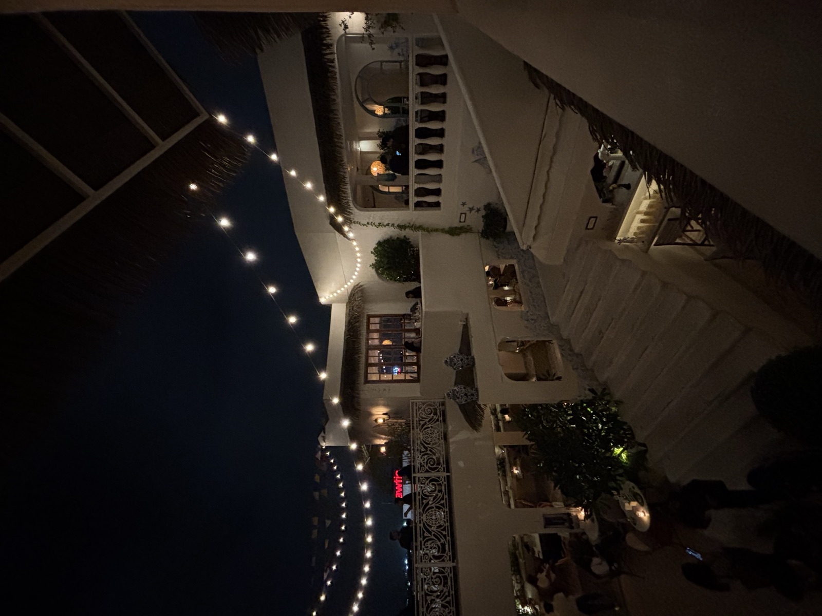 String lights strung over the whitewashed terraces of a rooftop lounge at night