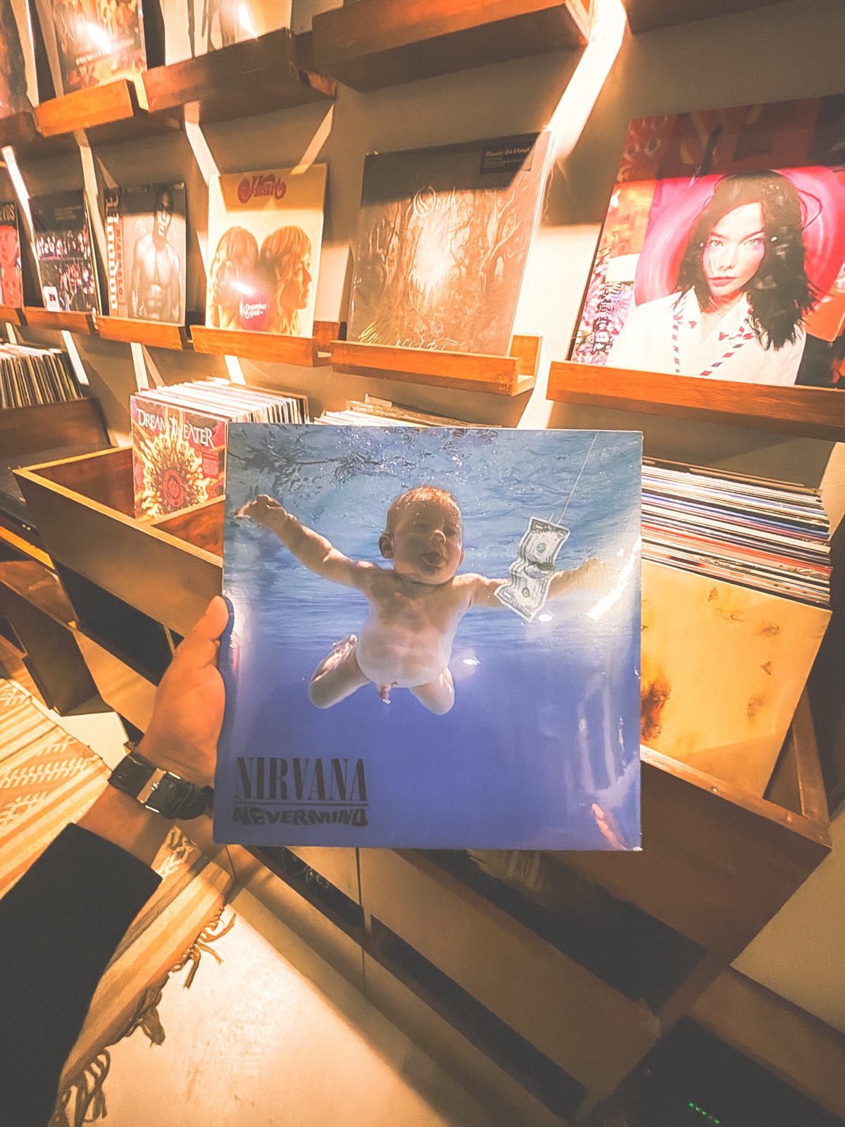 Holding Nirvana's Nevermind LP in a record store, rows of vinyl on the shelves behind